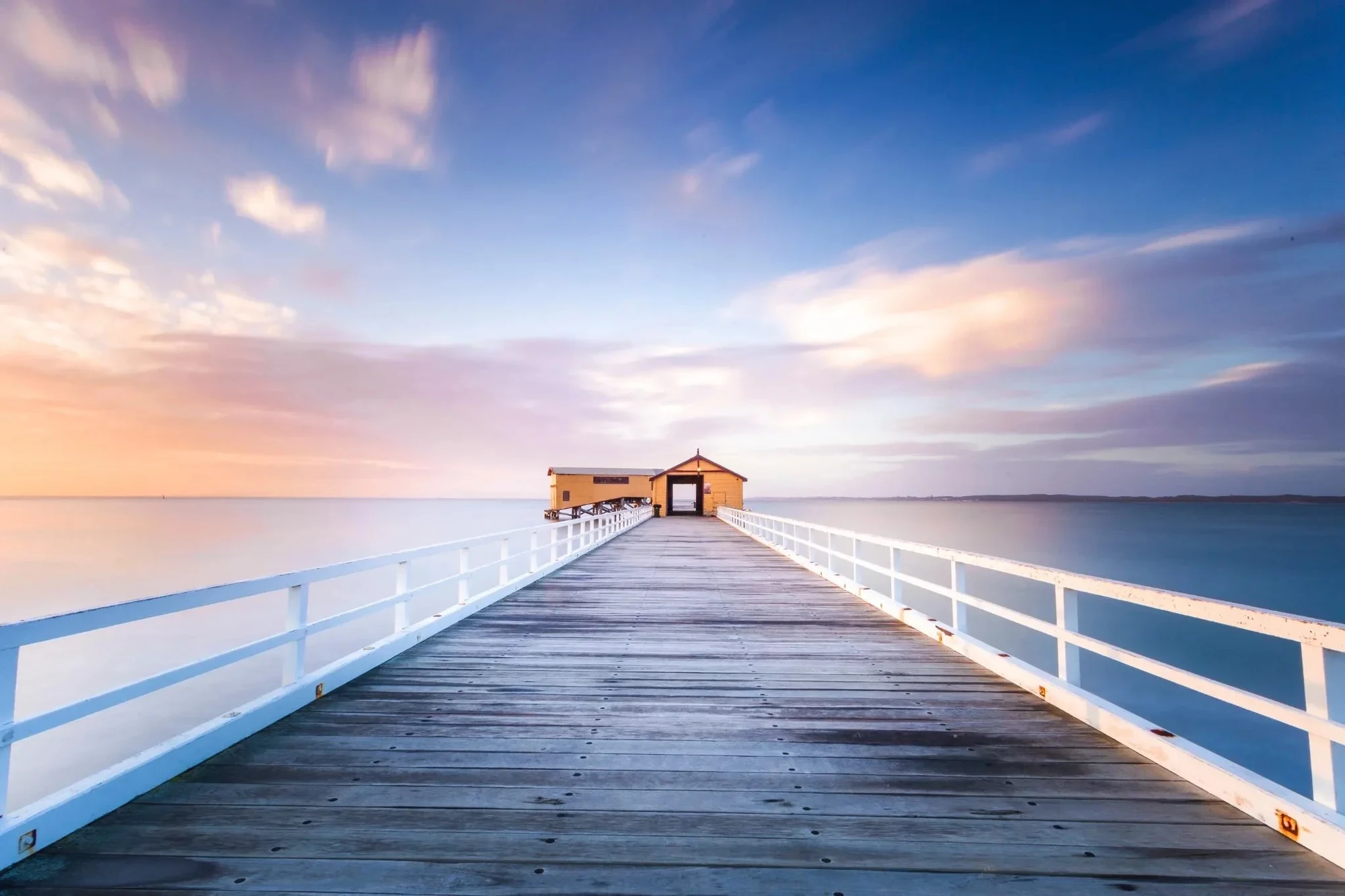 Wooden jetty stretching into calm water at sunrise on the Central Coast