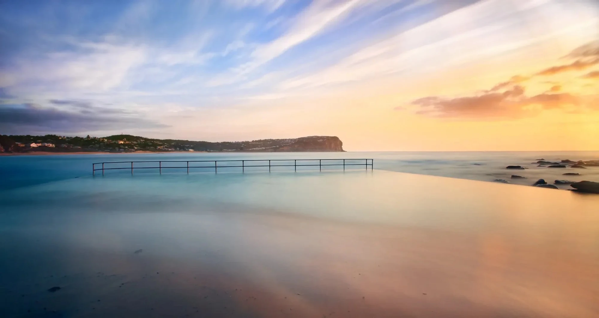 Macmasters Beach ocean pool at sunrise with soft waves and distant headland, Central Coast NSW